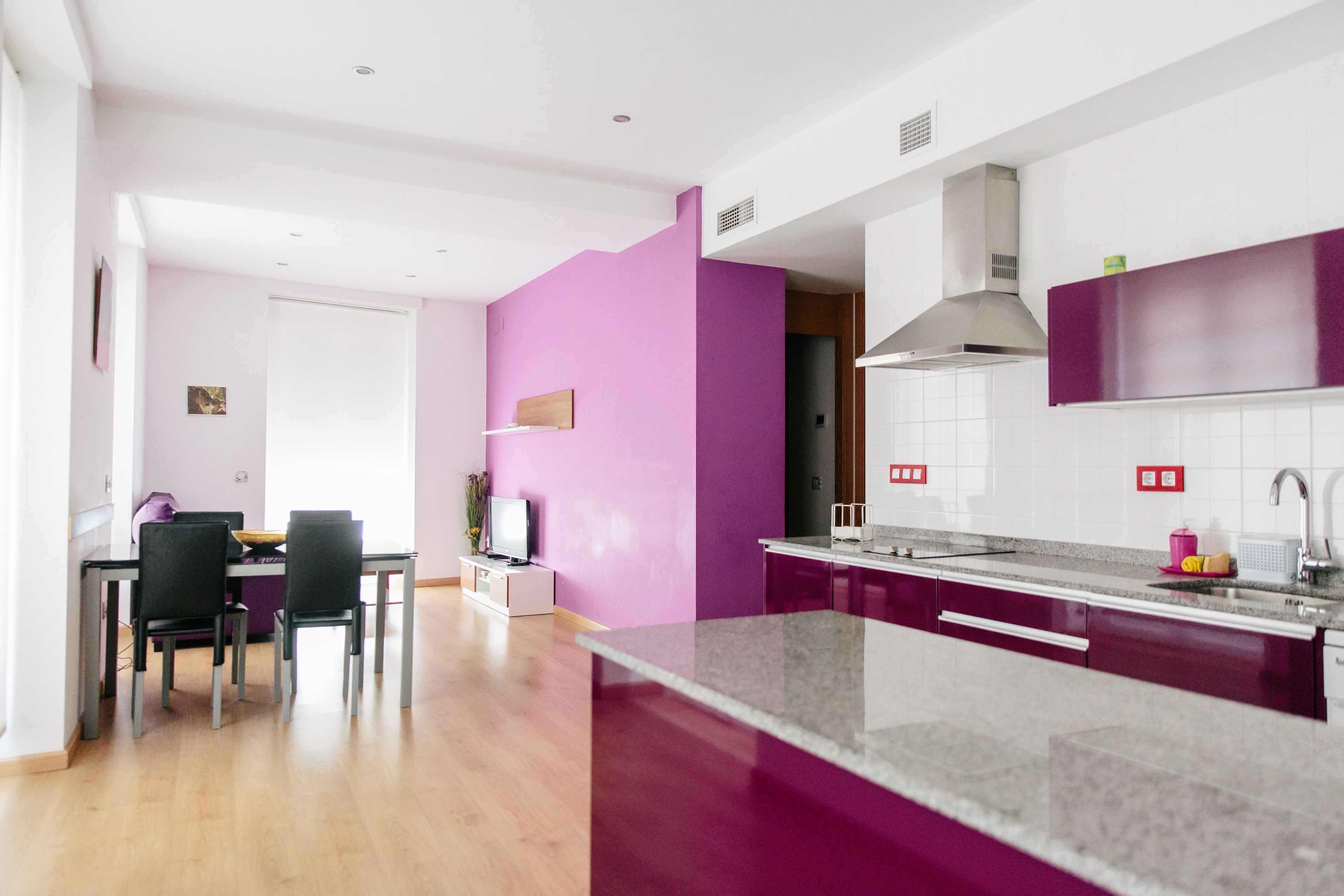 A modern kitchen with a marble island, wooden dining table, and chairs.