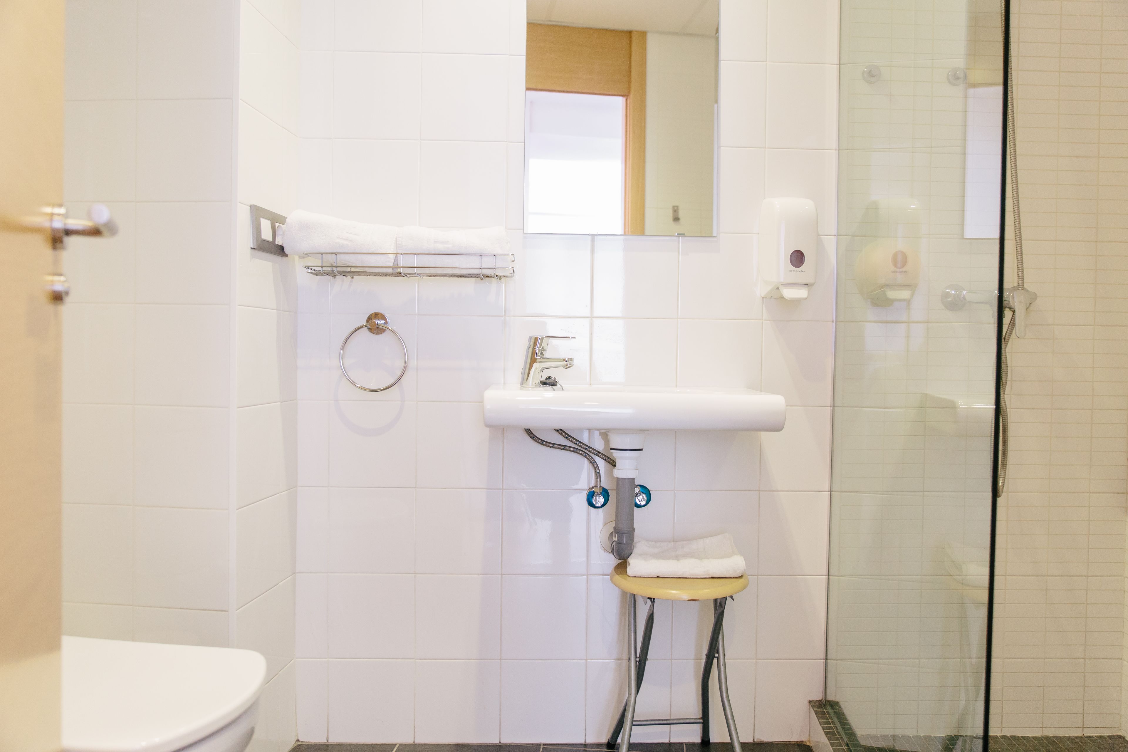 A bathroom with a toilet, sink, and glass shower enclosure.