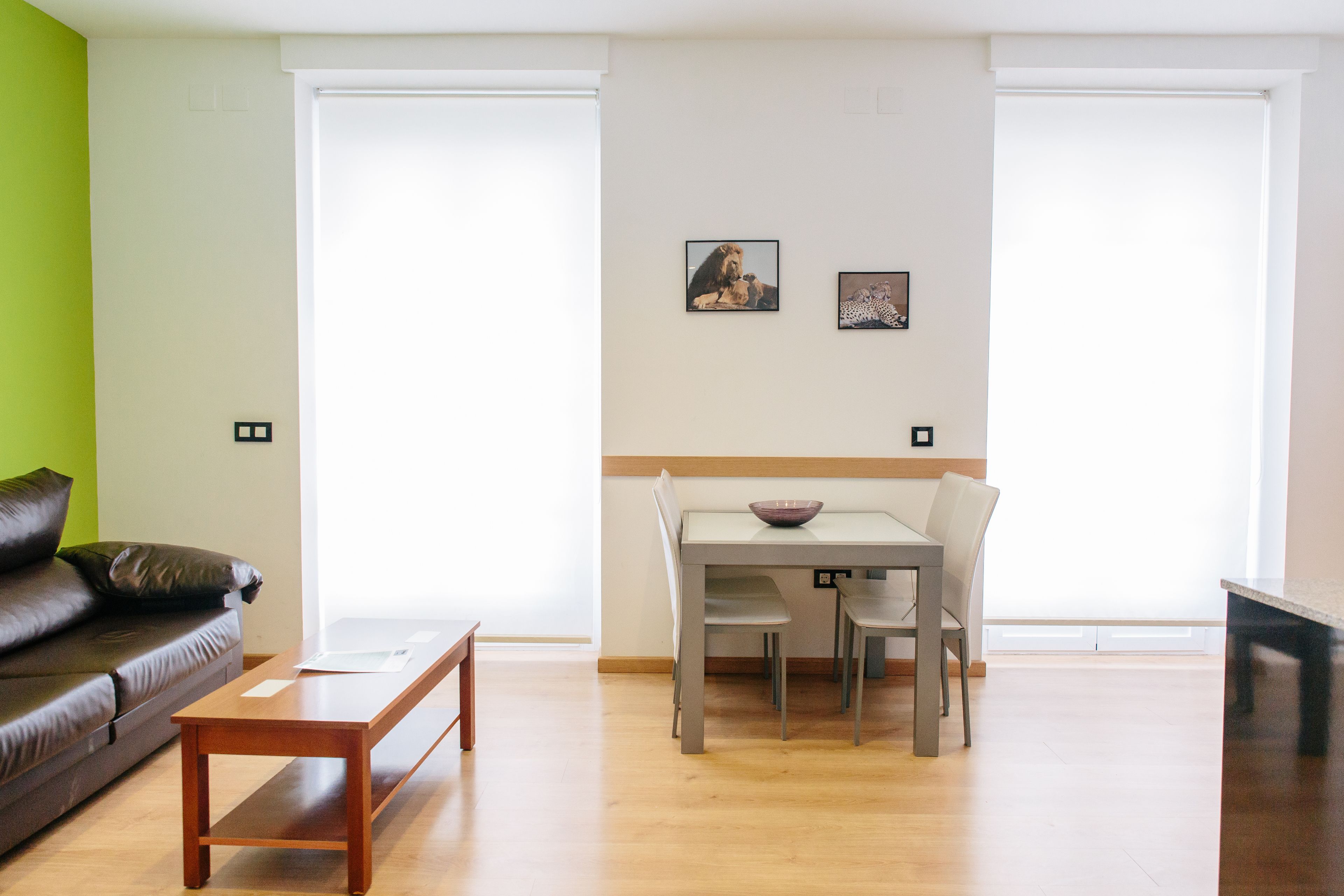 Una sala de estar con un sofá de cuero marrón, una mesa de centro de madera y un comedor con una mesa y sillas.