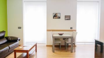 Una sala de estar con un sofá de cuero marrón, una mesa de centro de madera y un comedor con una mesa y sillas.
