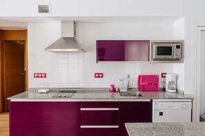 Uma cozinha moderna com micro-ondas integrado, cafeteira e escorredor de louça.