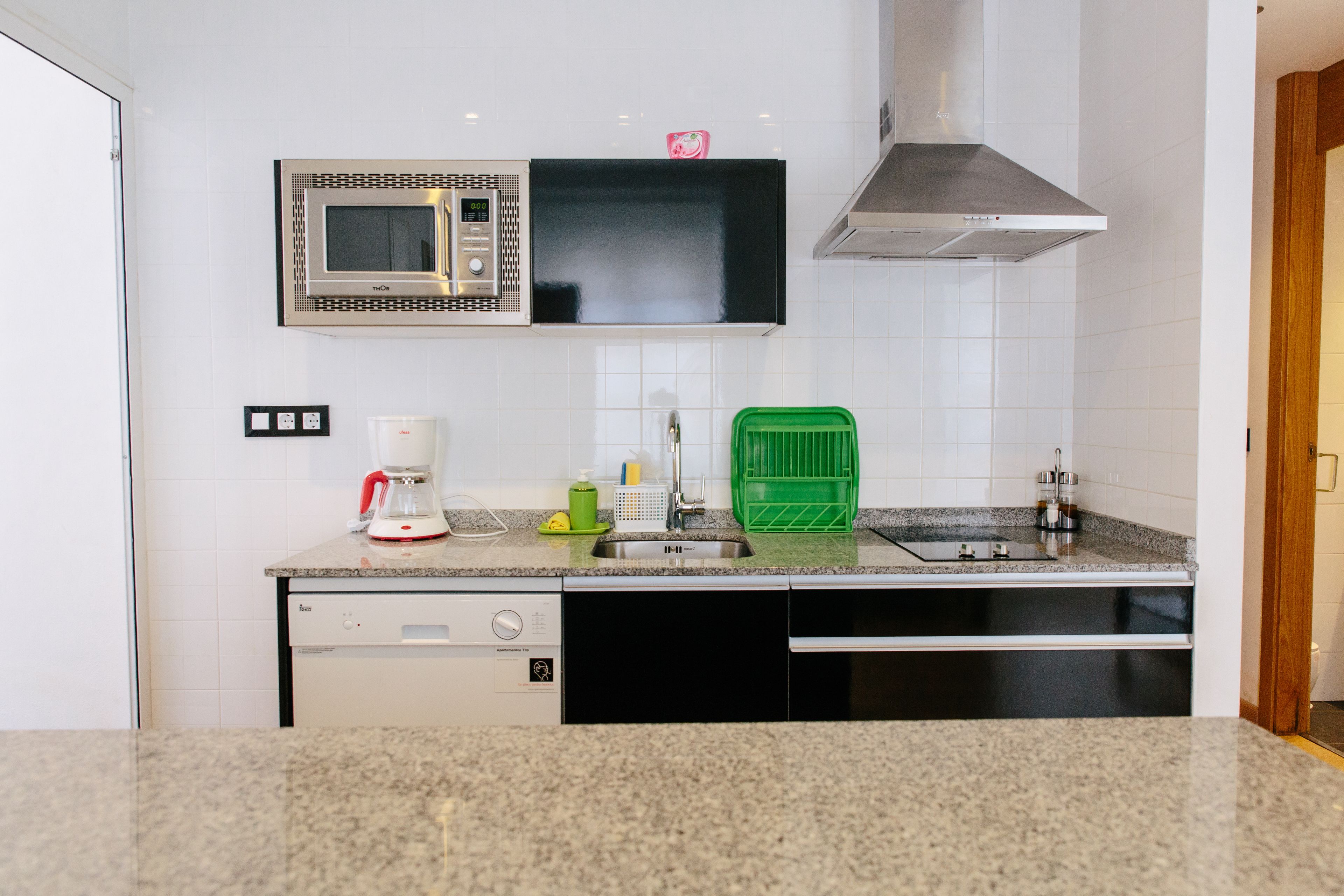 A kitchen with a microwave, coffee maker, and green dish rack.