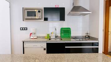 A kitchen with a microwave, coffee maker, and green dish rack.