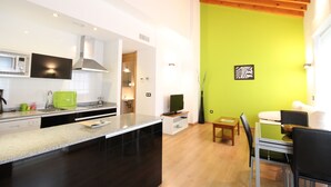 A modern kitchen with a granite countertop, stainless steel appliances, and a wooden ceiling.