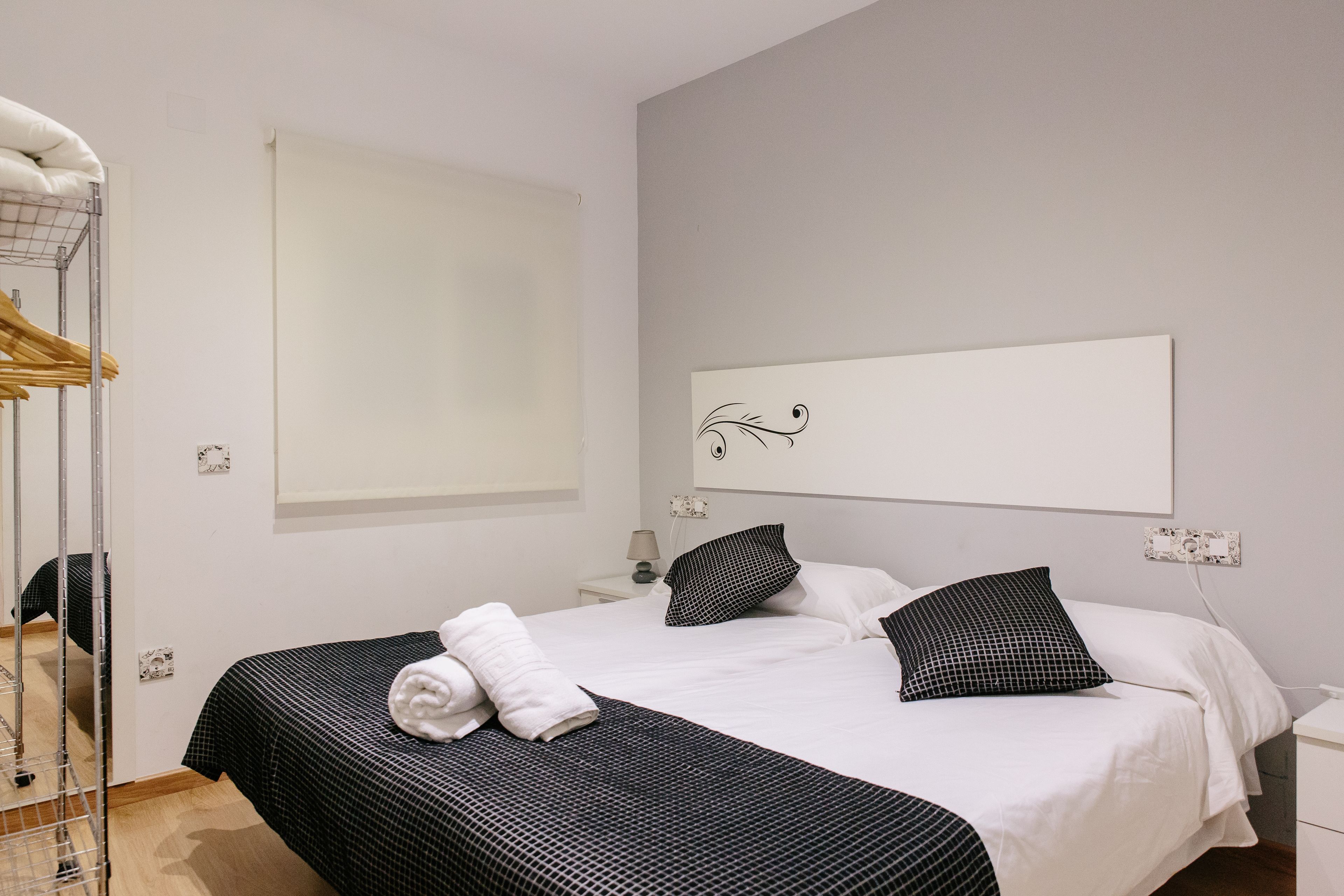 Una habitación de hotel con una cama grande, una mesita de noche, un espejo y un armario.