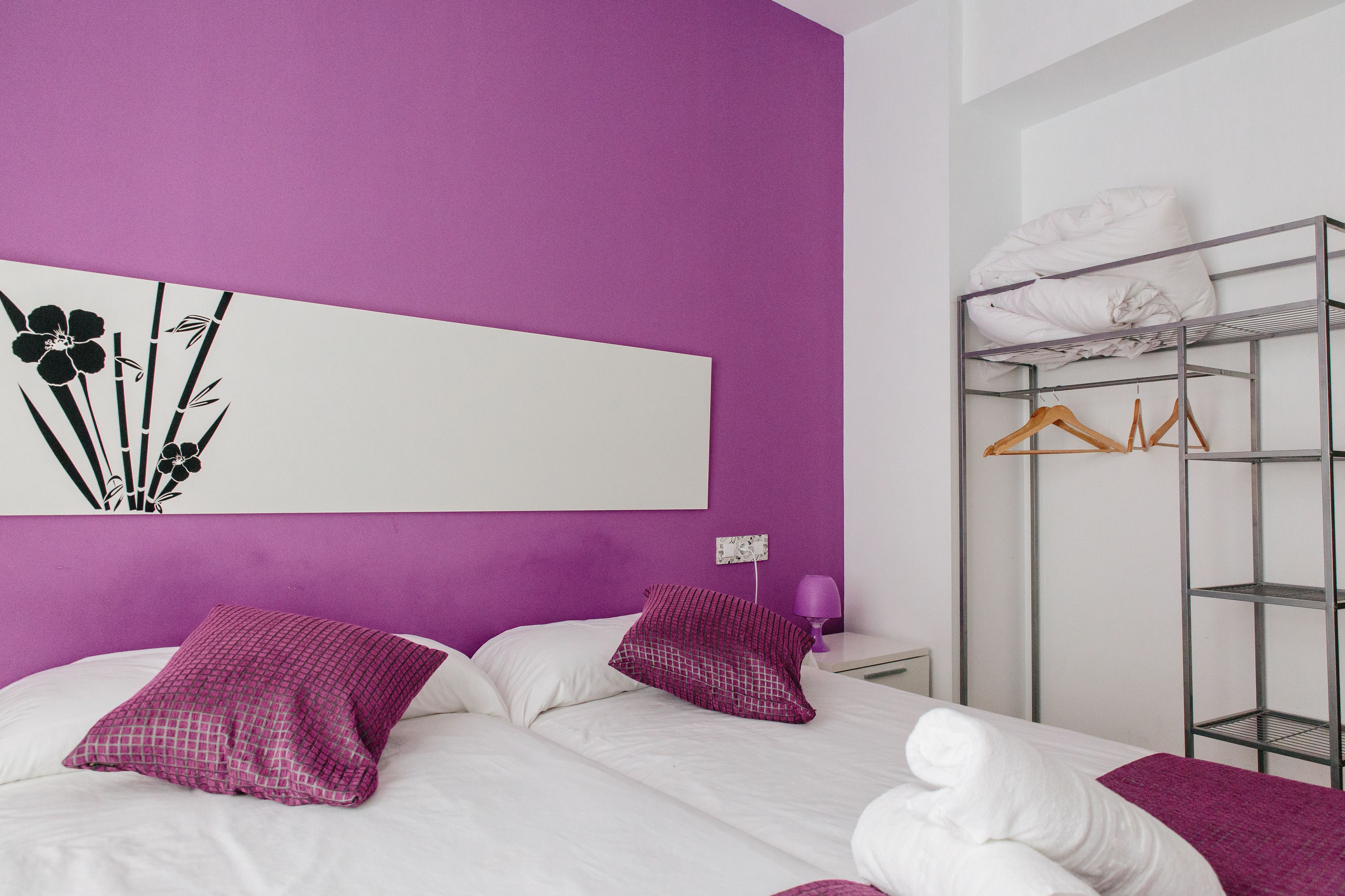 Una camera da letto con un letto, cuscini, un armadio e un'opera d'arte a parete.