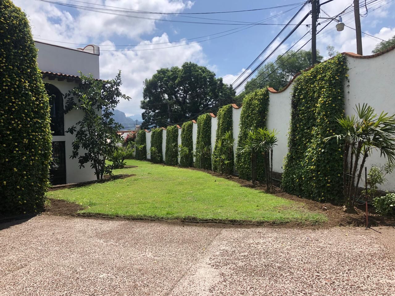 Un camino de entrada estrecho y pavimentado que conduce a un edificio blanco con techo de tejas.
