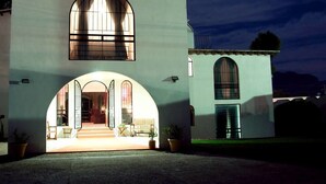 Un edificio de dos pisos con una amplia entrada en arco y un ventanal arqueado más pequeño en el nivel superior.