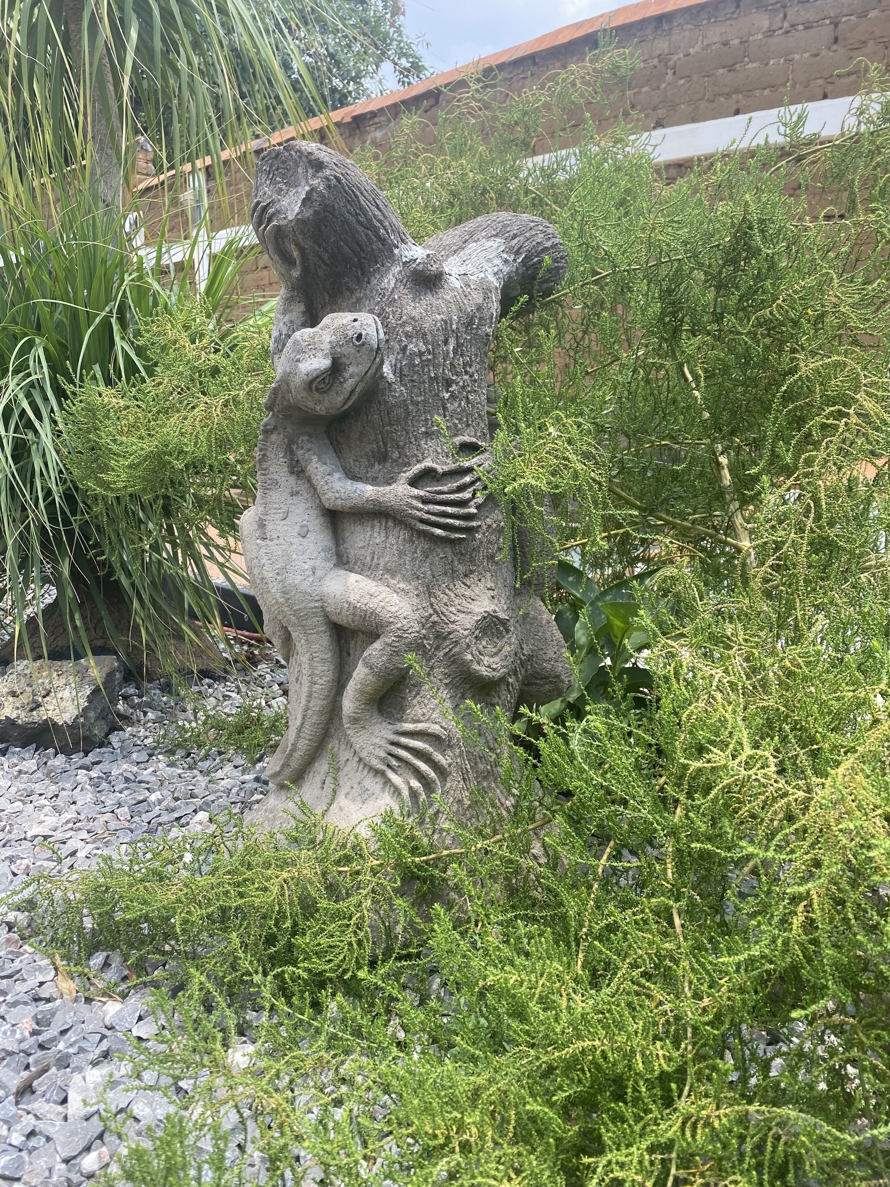 A stone sculpture of a frog and a snake in a garden setting.