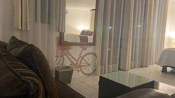 Une chambre d’hôtel avec un grand miroir, une décoration murale sur le thème du vélo, un canapé, une petite table et une lampe.