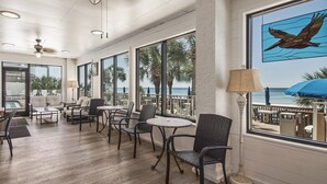 Ein geräumiger Innenbereich mit großen Fenstern, einem Deckenventilator und Blick auf den Strand.