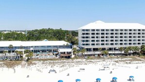 Ein Strandhotel mit mehreren Gebäuden, einem Poolbereich und Liegestühlen.