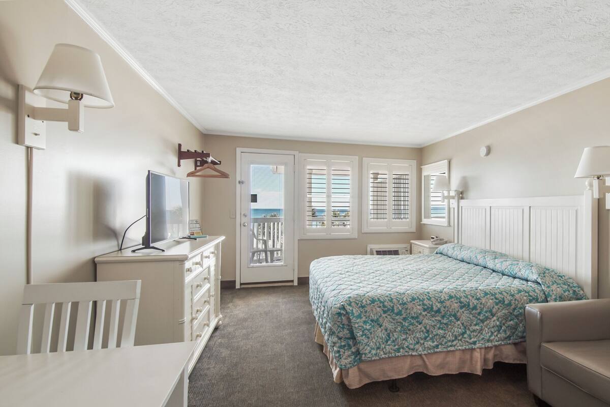Ein Schlafzimmer mit Bett, Schreibtisch, Stuhl und Fernseher.