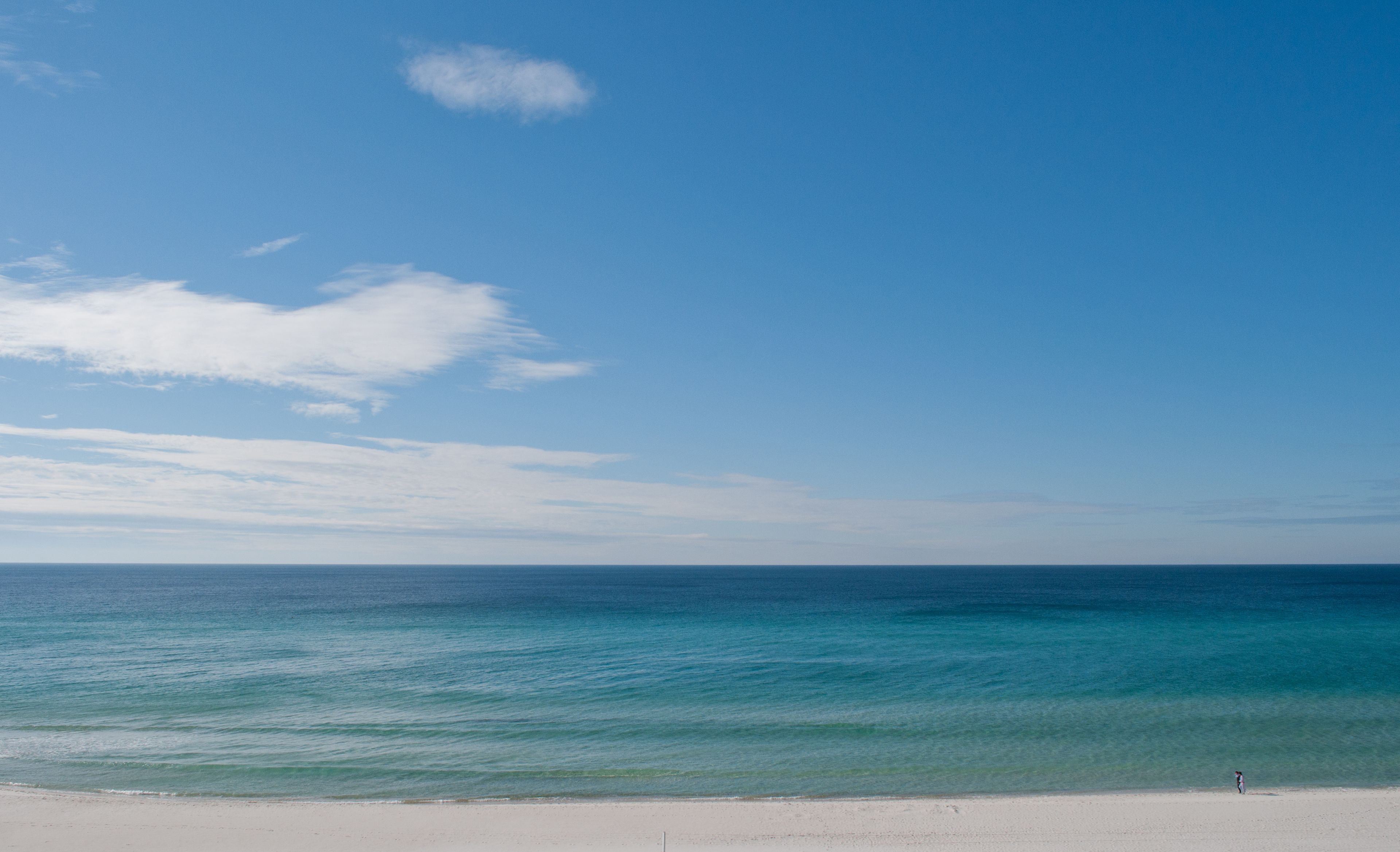 A beach with clear blue water and a sandy shore.