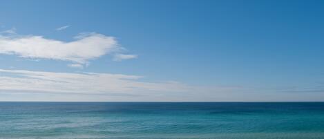 A beach with clear blue water and a sandy shore.