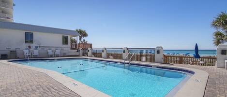 A rectangular swimming pool with a clear blue water, surrounded by a brick deck.