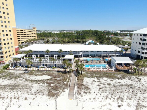 Un hôtel doté d’une grande piscine, de nombreux chaises longues et offrant une vue sur la plage.