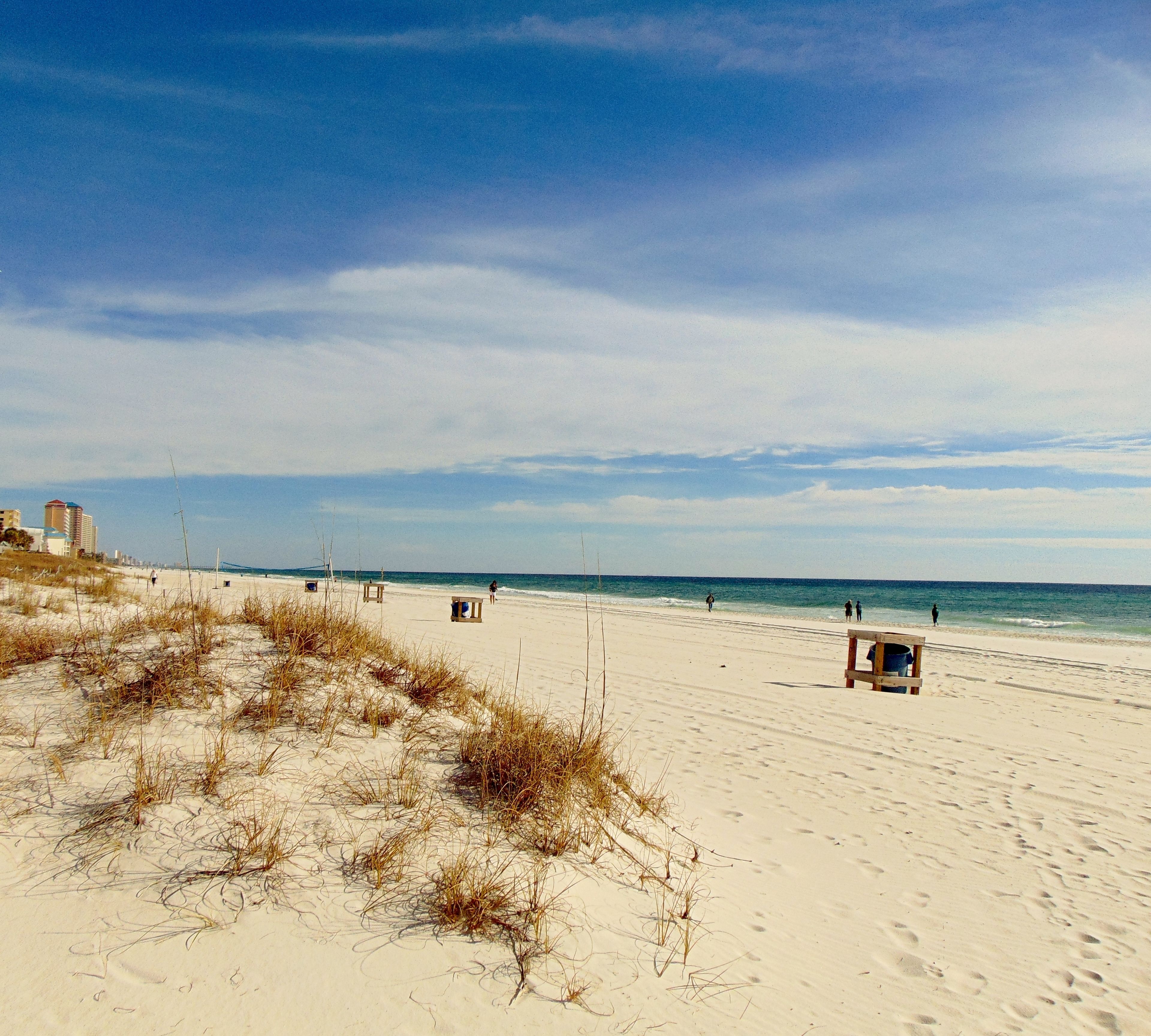 A beach with a lifeguard tower, sandy dunes, and a clear sky.