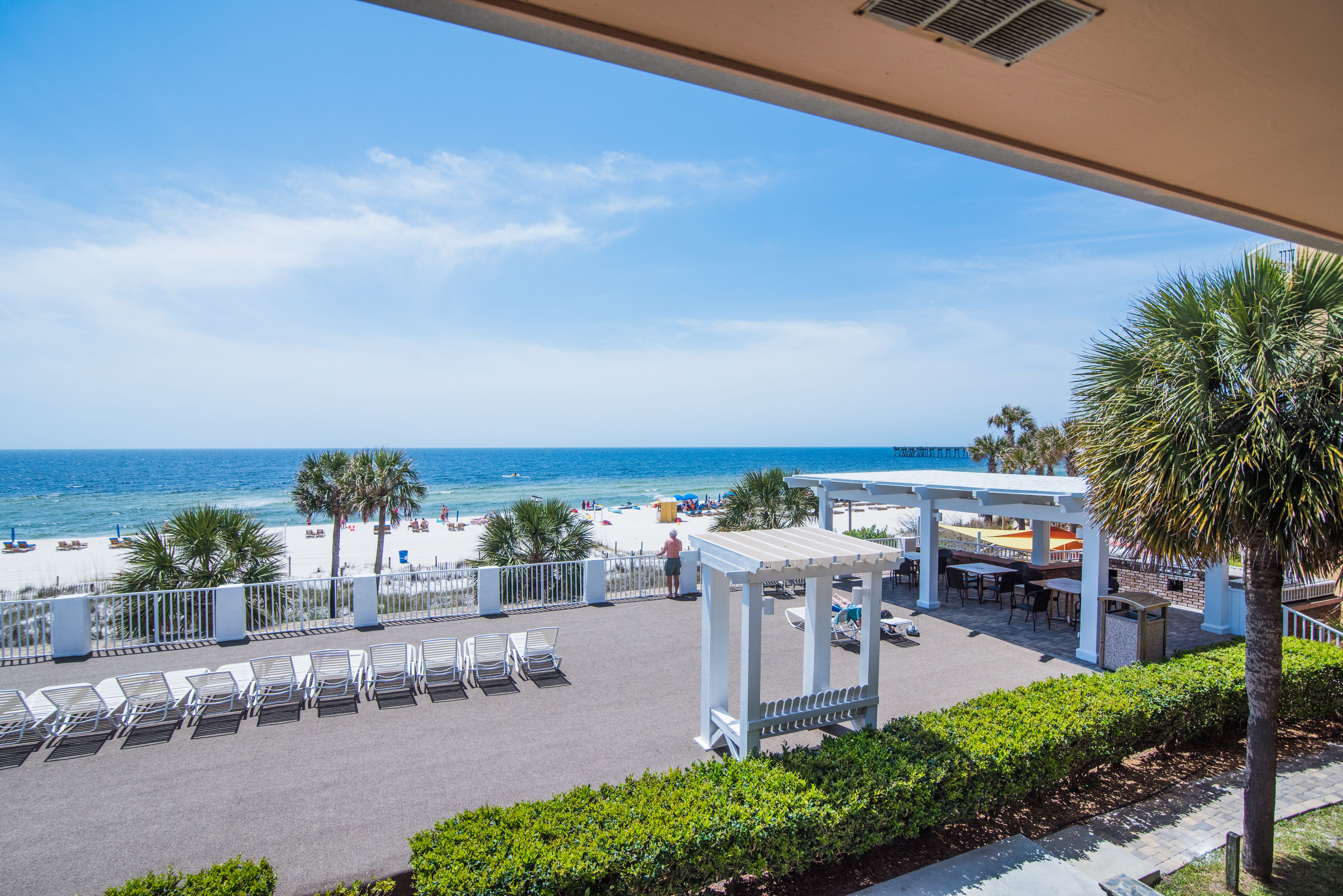 A beachside patio with lounge chairs, a covered seating area, and a view of the ocean.