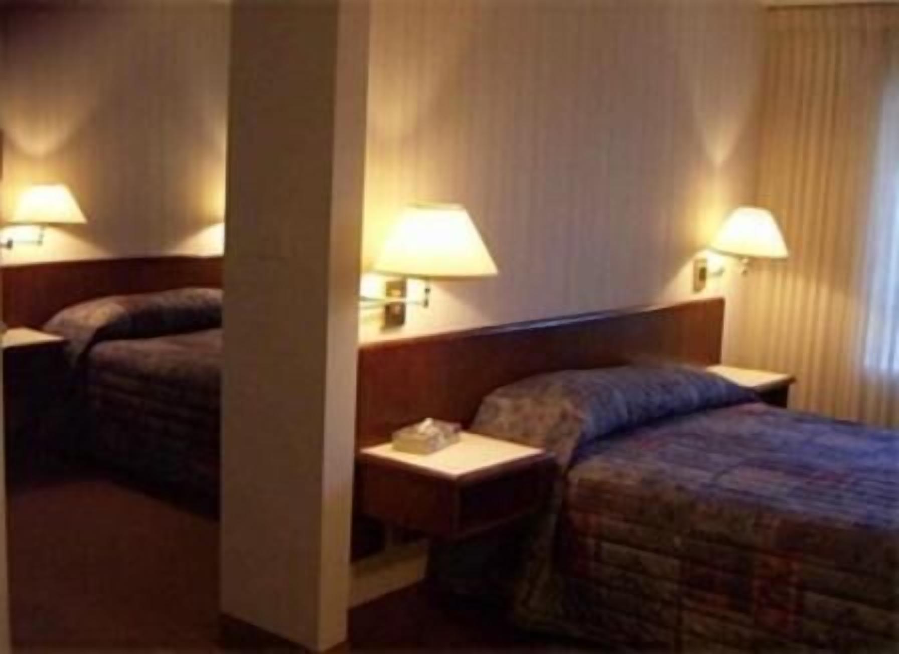 Een hotelkamer met een bed, twee nachtkastjes en lampen.