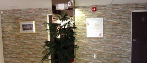 A lobby with a tiled floor, a stone wall, a potted plant, and a door.