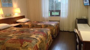Habitación de hotel con dos camas, un escritorio, una silla, un televisor y una ventana con cortinas.