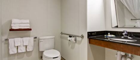 A bathroom with a toilet, a sink, a mirror, and a towel rack.