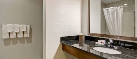 A bathroom with a sink, mirror, and towel rack.