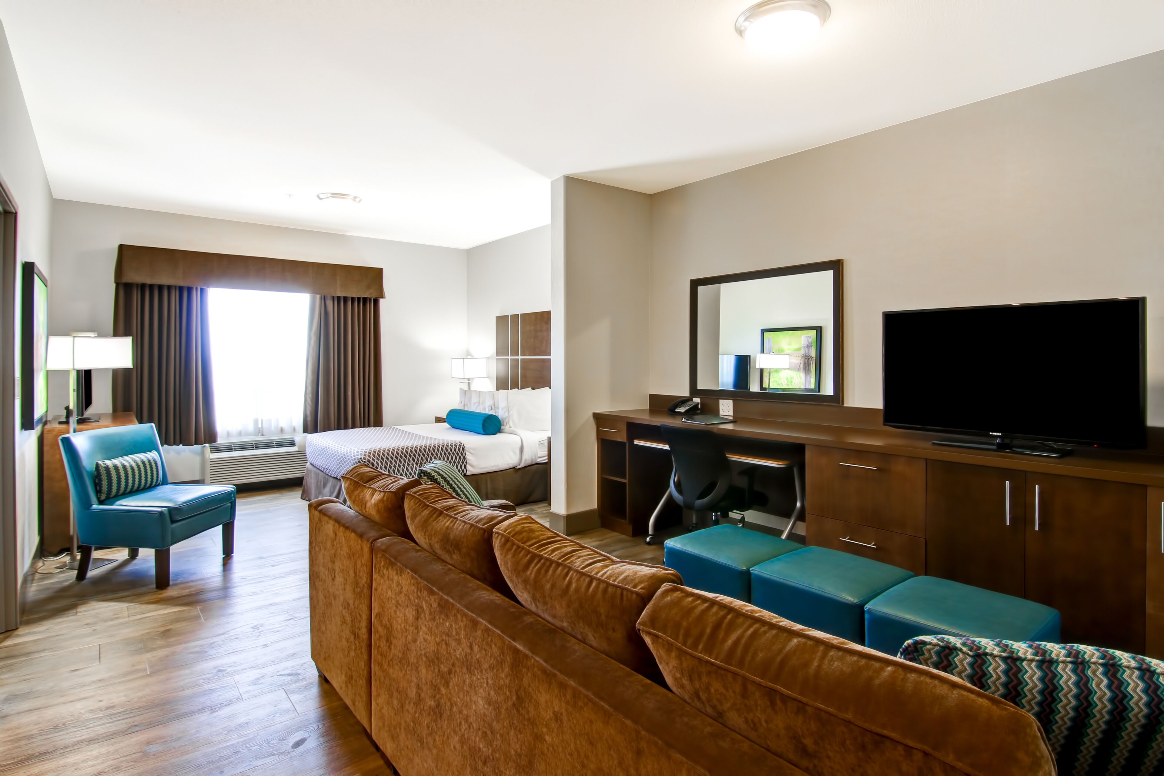 A hotel room with a bed, a desk, a television, a sofa, and a chair.