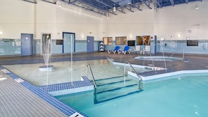 Una piscina interior con varias pistas, un trampolín y sillones de descanso.