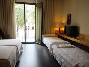 A hotel room with two beds, a television, and a window with curtains. - Hospedería Pax (León)