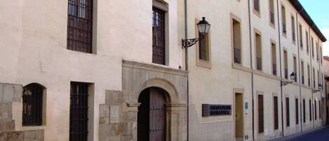 A historic building with a stone facade, multiple windows, and a cobblestone street.