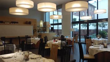 Un restaurant doté de nombreuses tables, de chaises et de luminaires suspendus.