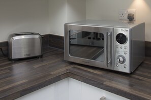 A kitchen with a toaster and a stainless steel microwave oven.