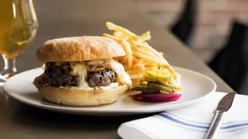 Un plato con una hamburguesa, papas fritas y pepinillos.
