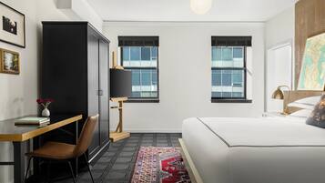 A modern bedroom with a bed, a desk, a chair, a wardrobe, and two windows.