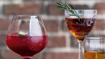 Tres vasos de bebidas distintas sobre una mesa, con un fondo de pared de ladrillo.