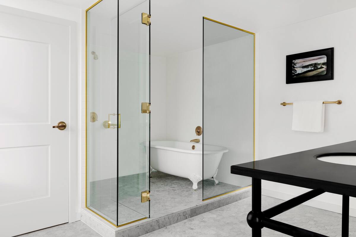 A modern bathroom with a glass-enclosed shower, a white bathtub, and a black vanity.