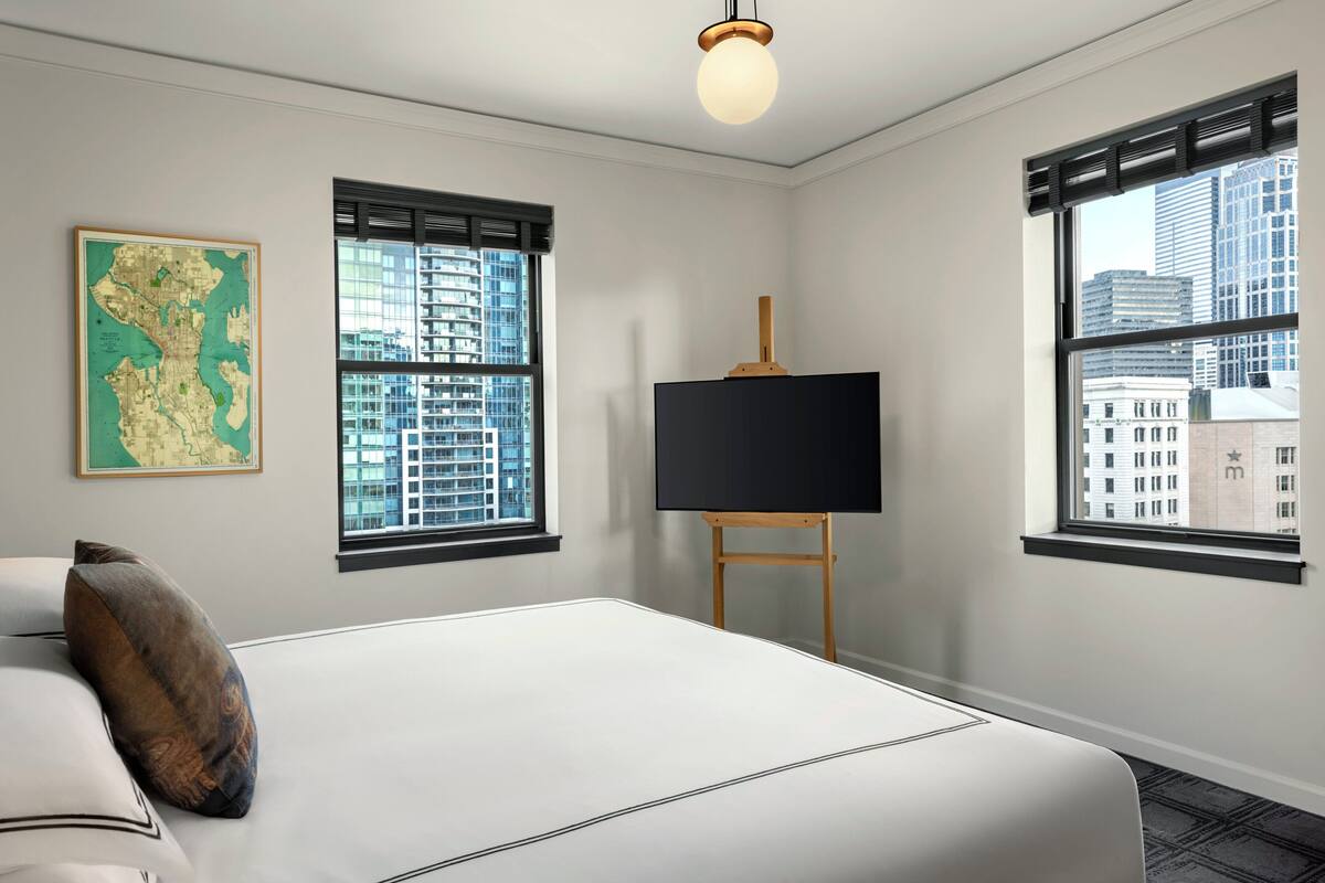 A hotel room with a large bed, a map on the wall, and a TV on a stand.