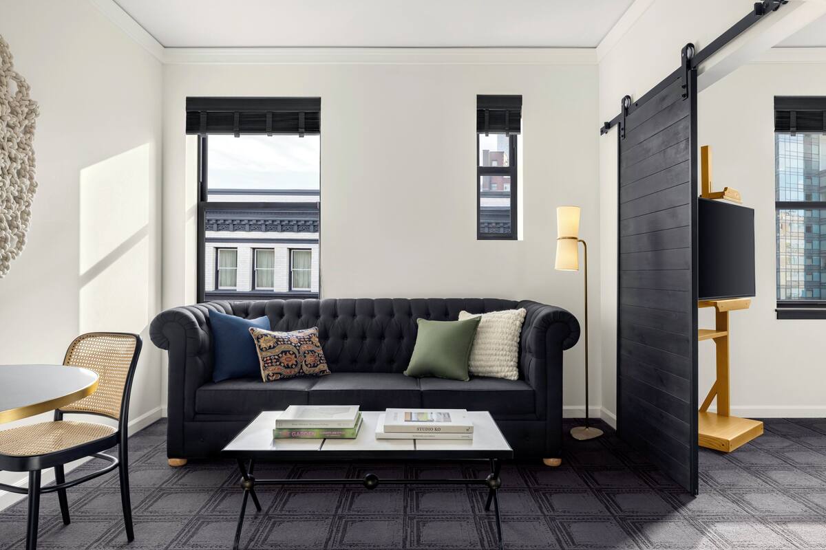 A modern living room with a black sofa, a coffee table, a chair, and a bookshelf.