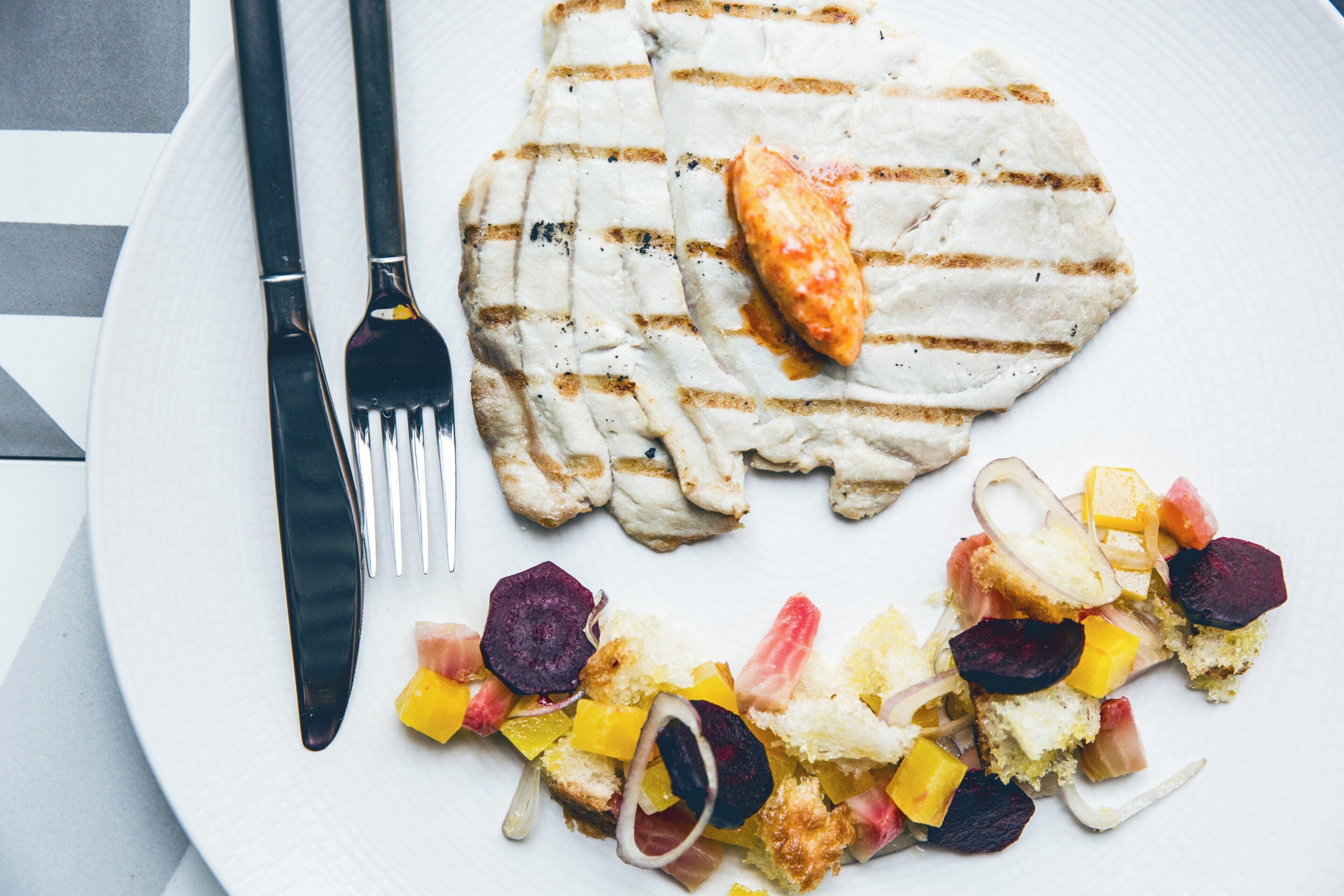 A plate with grilled meat, a piece of fried chicken, and a side of mixed vegetables.