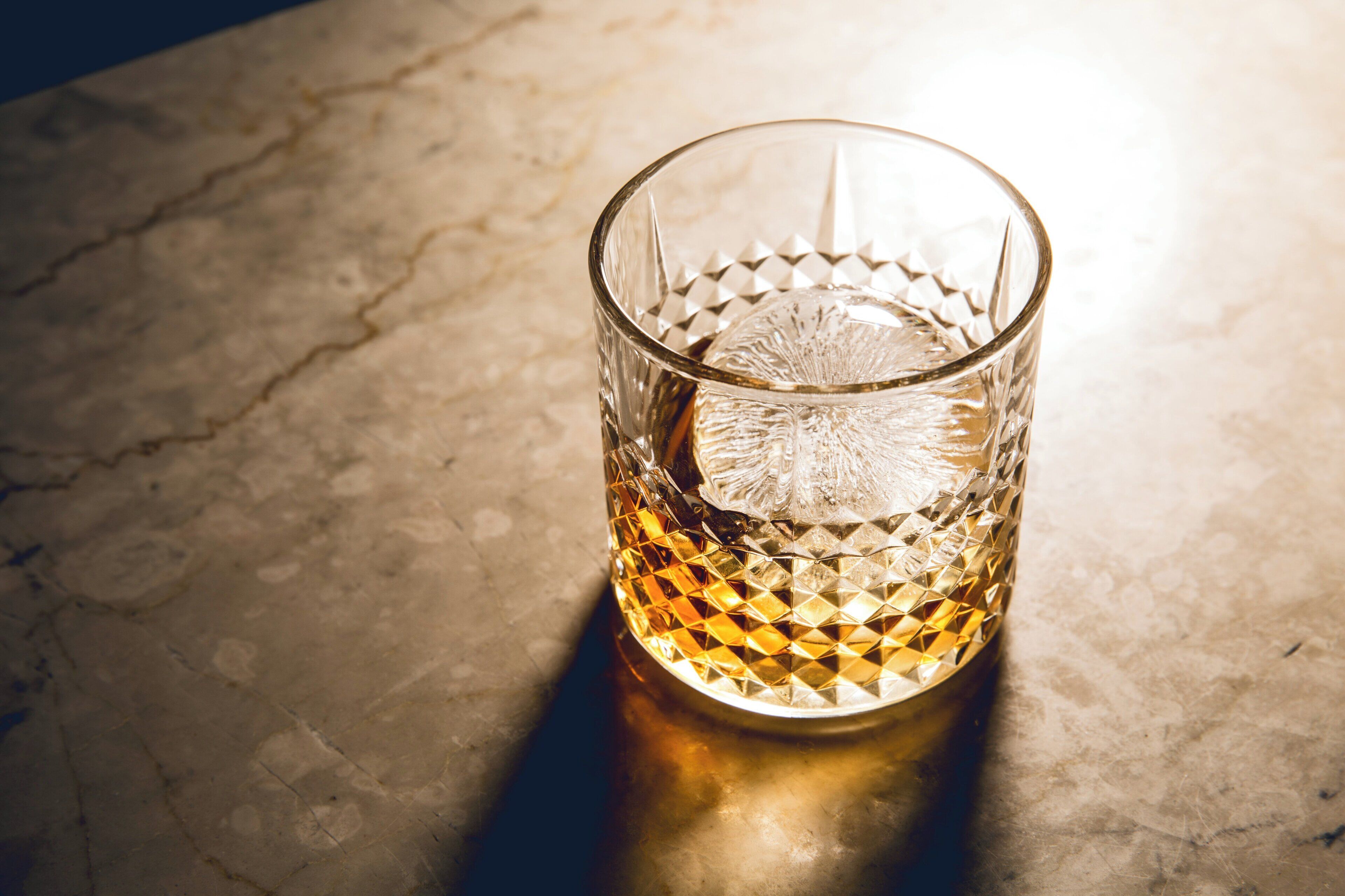 A clear glass tumbler with a textured pattern on a textured surface.