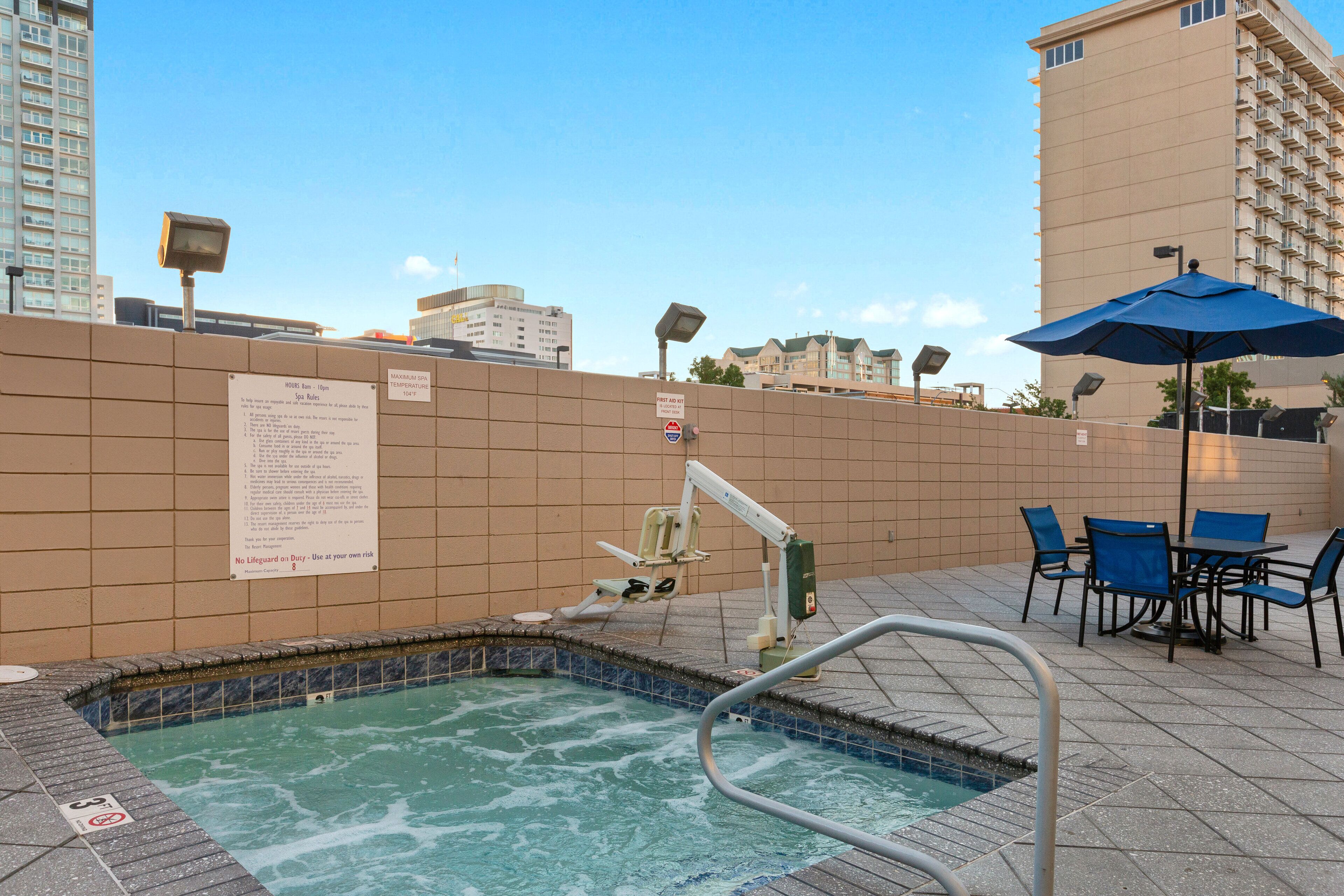 Un área de piscina en la azotea con jacuzzi, asientos y vistas del horizonte urbano.