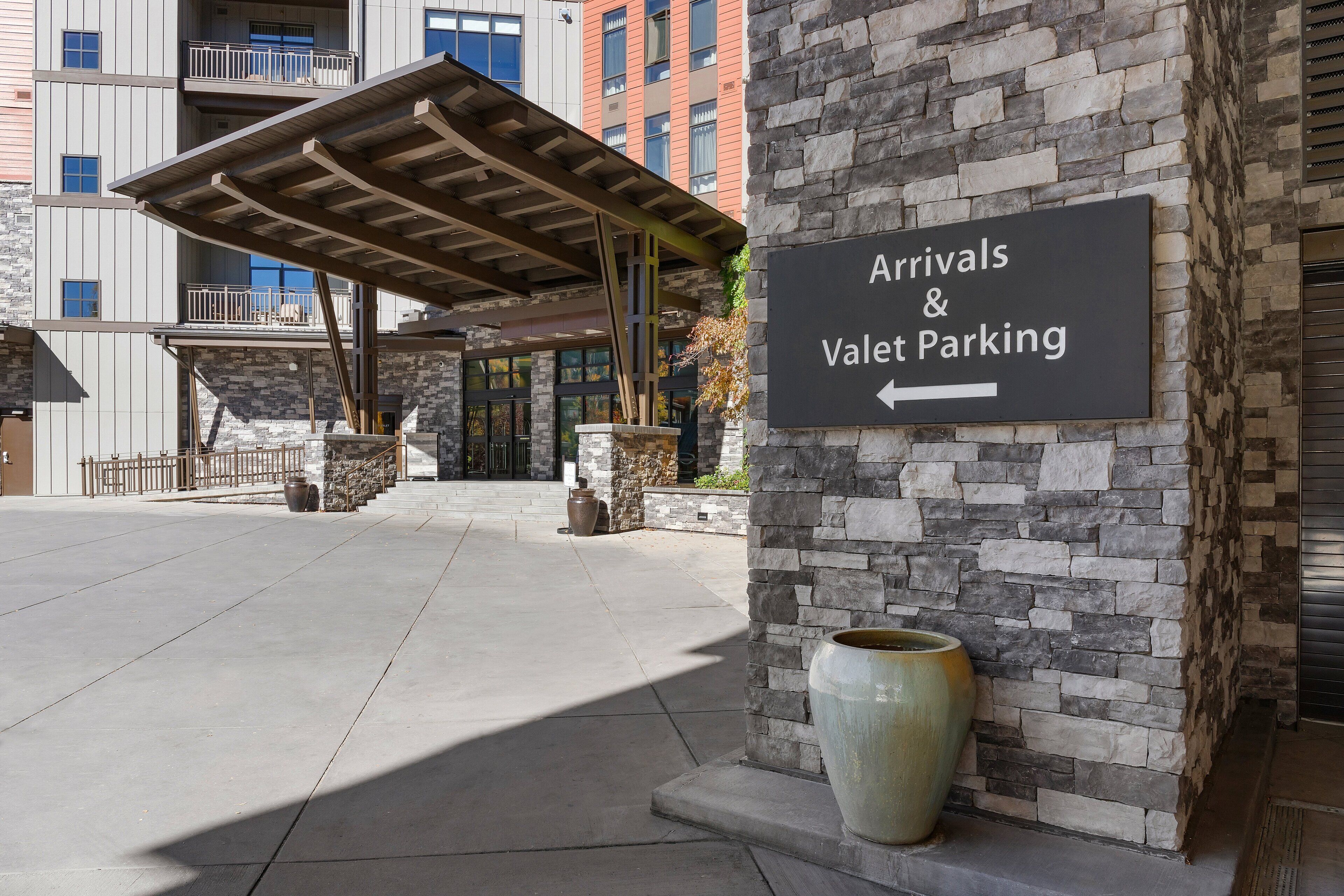A sign for 'Arrivals & Valet Parking' with a building entrance in the background.