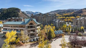 A hotel with a central building featuring a green roof, surrounded by parking and autumn-colored trees. - Club Wyndham Resort at Avon (Avon)