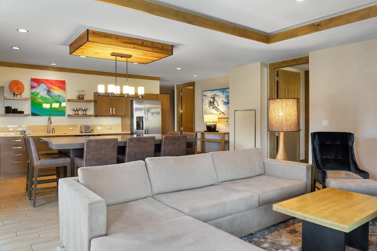 A modern living room with a sofa, a coffee table, and a dining area with chairs and a table.