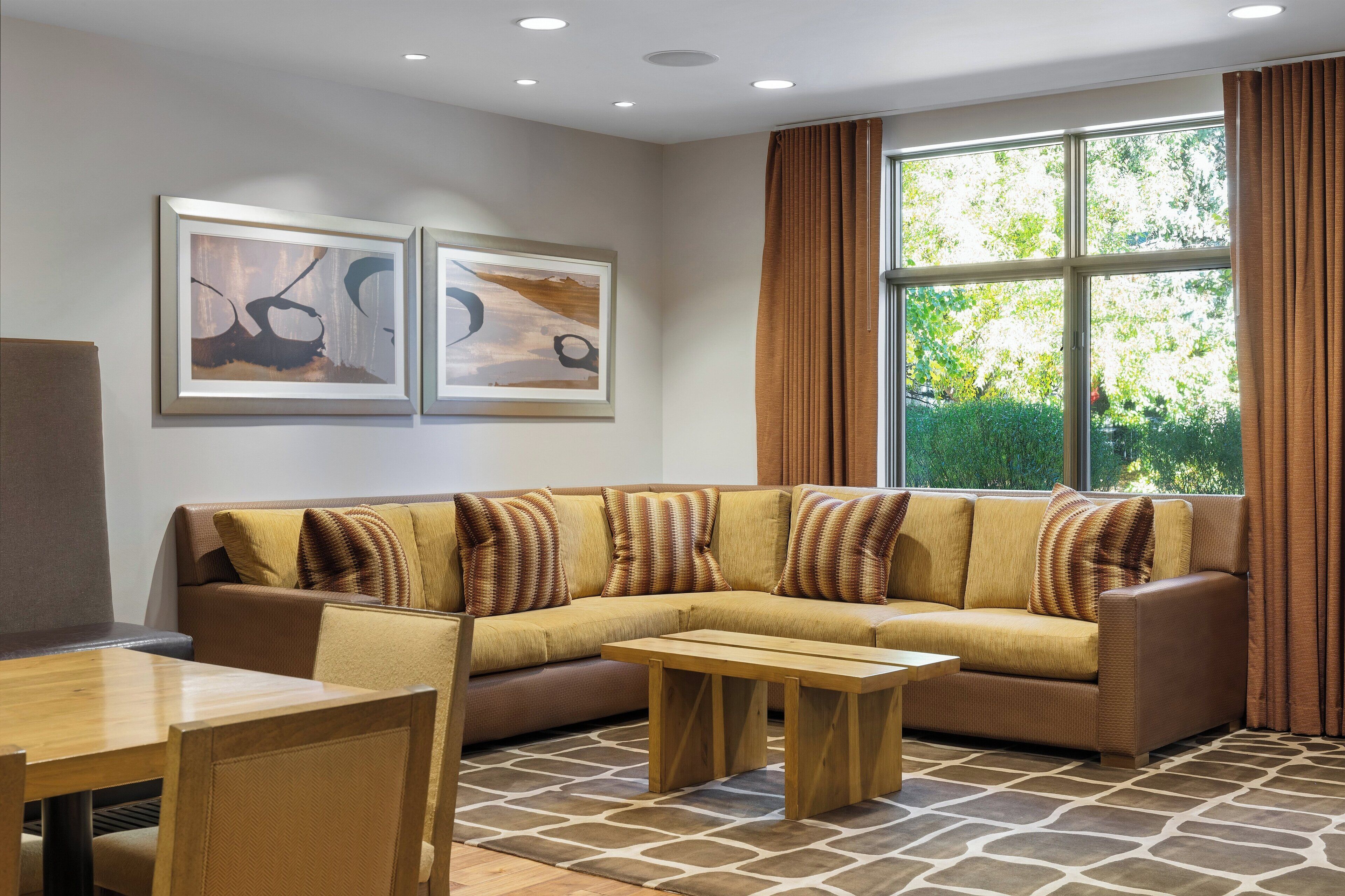 A modern living room with a sectional sofa, a wooden coffee table, and a dining area.