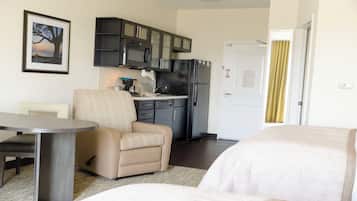 Habitación de hotel compacta con kitchenette, comedor y cama.