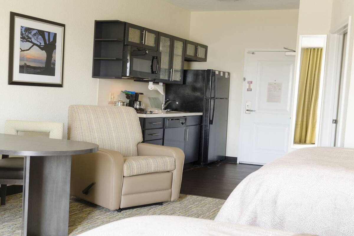 Habitación de hotel compacta con kitchenette, comedor y cama.