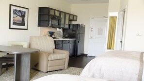 Ein kleines Hotelzimmer mit Küchenzeile, Essbereich und Bett.